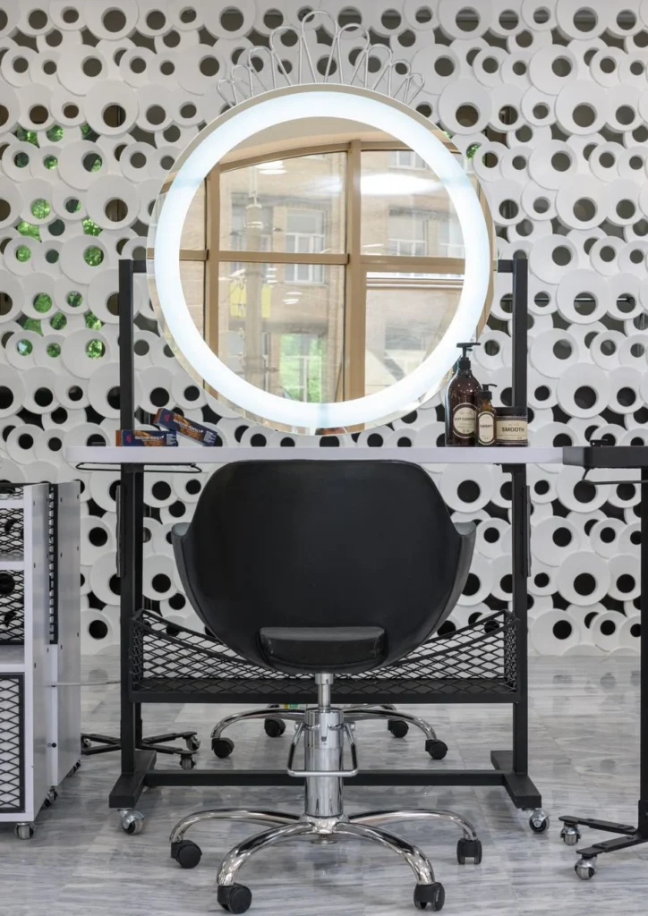 A stylish salon workstation featuring a ring light mirror and sleek black chair.